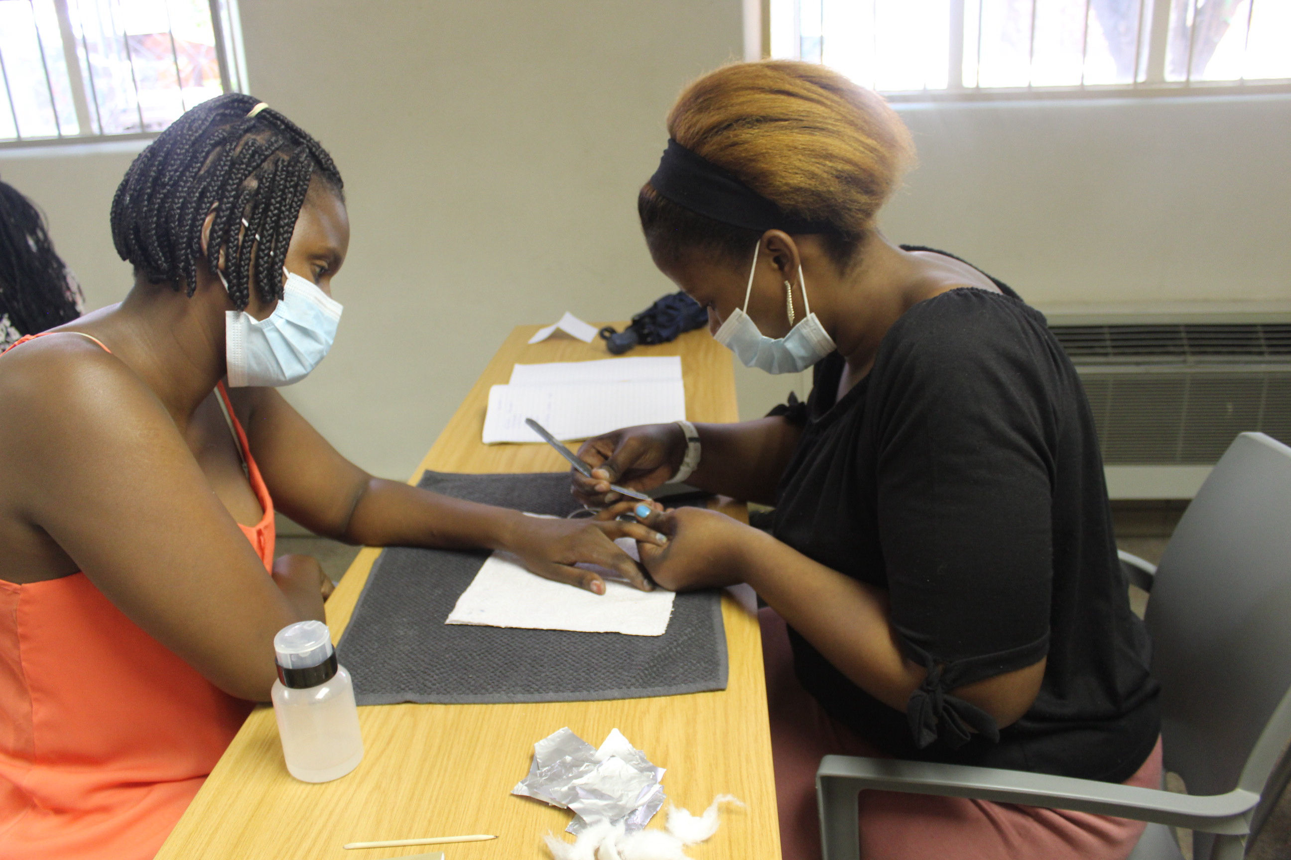 A couple of students learning how to do nails during the Outreach Foundation nail technician course
